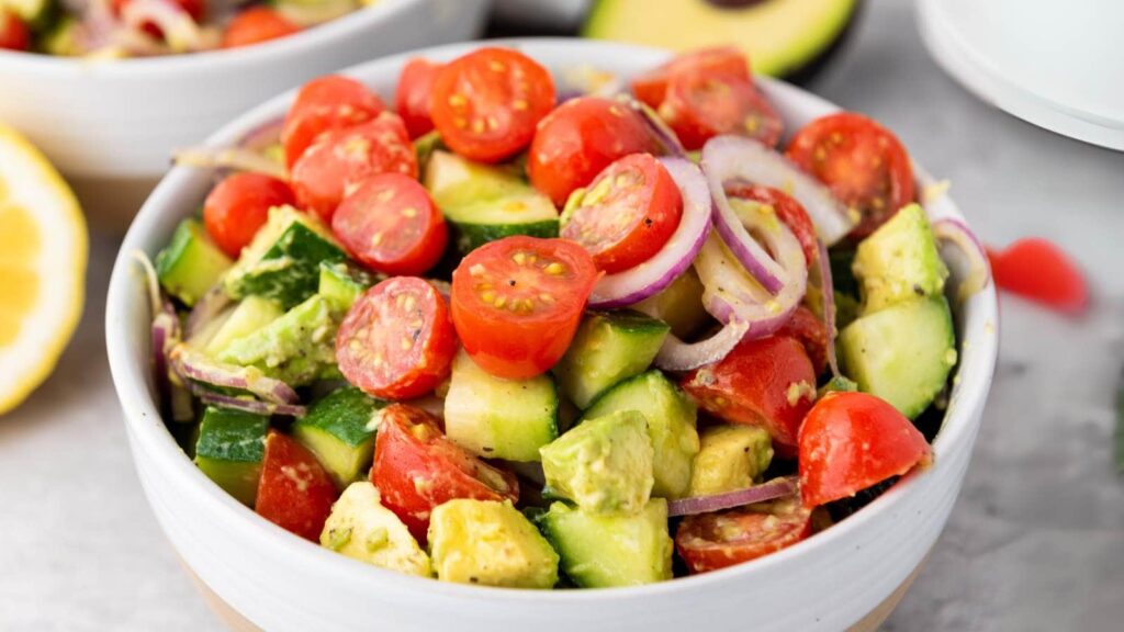 A bowl of avocado salad, tossed with dressing.