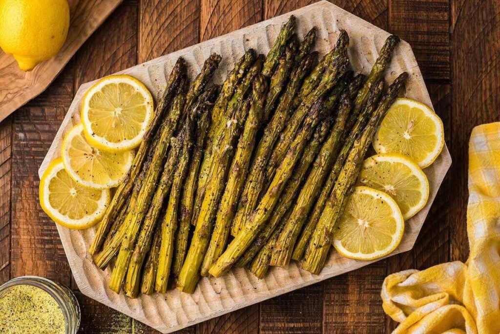 Smoked asparagus on a wooden cutting board with lemon slices.