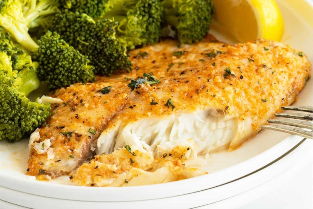 Parmesan Crusted Tilapia on a white plate with broccoli.