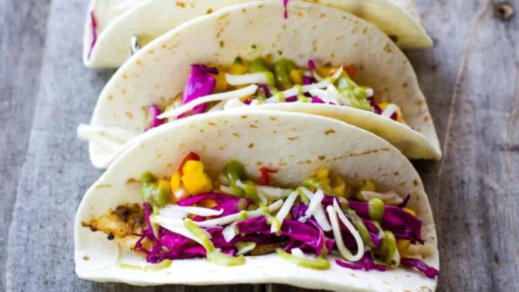 Grilled rockfish tacos assembled on a blue board.