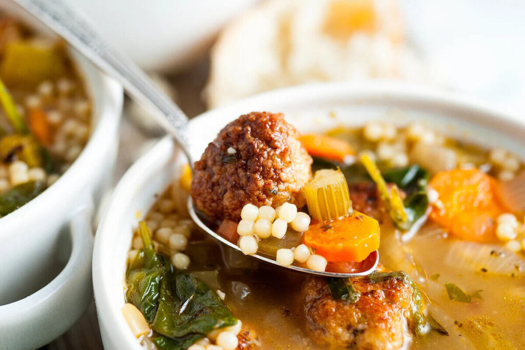 A spoon taking a scoop out of a homemade Italian wedding soup.