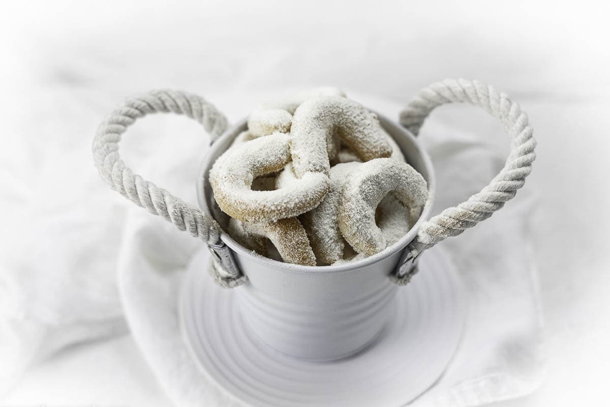 A container filled with almond crescent cookies.