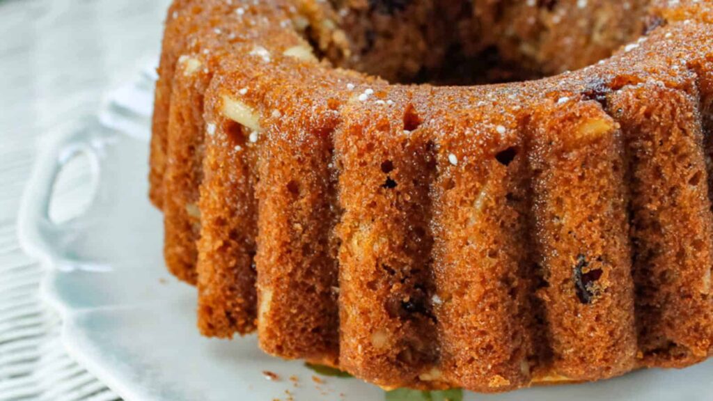 The image shows a close-up of a bundt cake on a white plate.