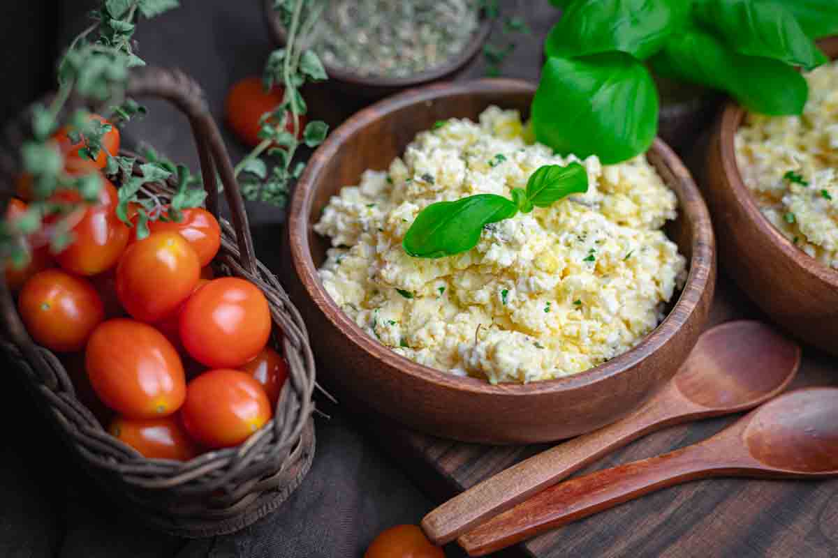 Bowl of creamy feta eggs garnished with basil.