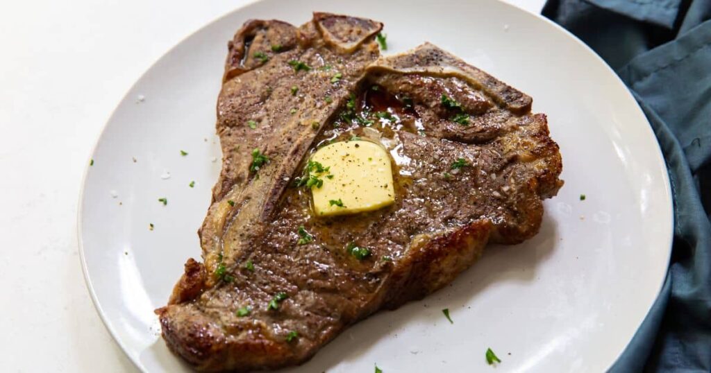 Air Fryer T-Bone Steak on a plate with pepper and parsley