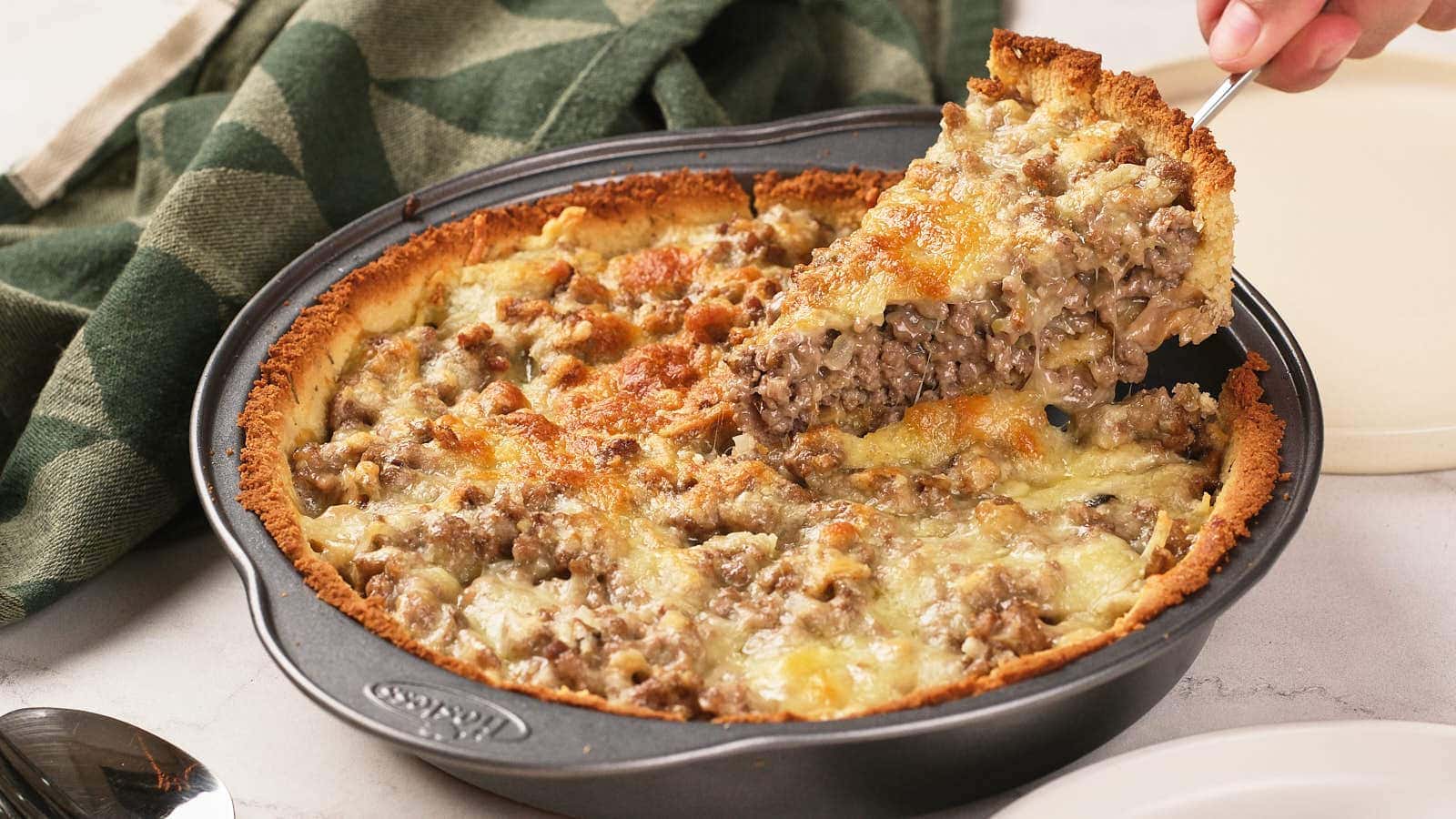 A slice of meat pie on a plate with green beans.