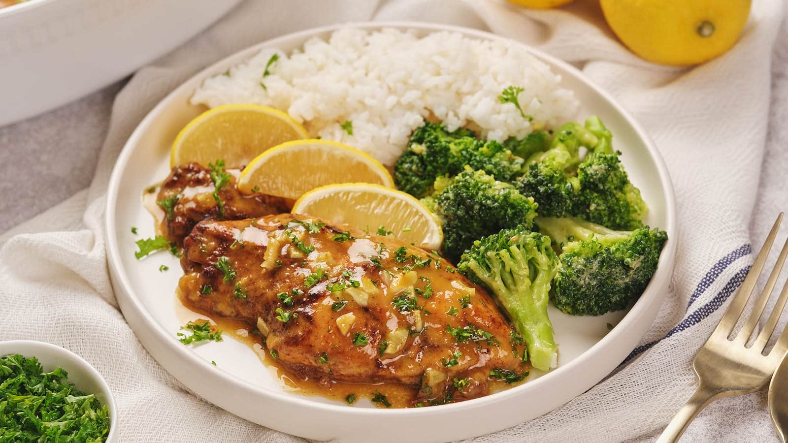 A plate with slow cooker honey mustard chicken, steamed broccoli, and white rice.