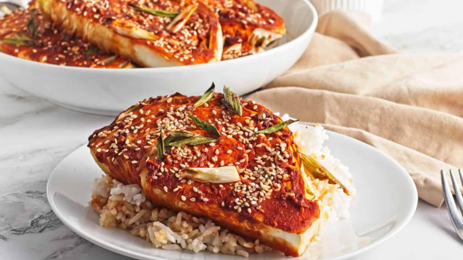 A gochujang cabbage steak on a bed of white rice.
