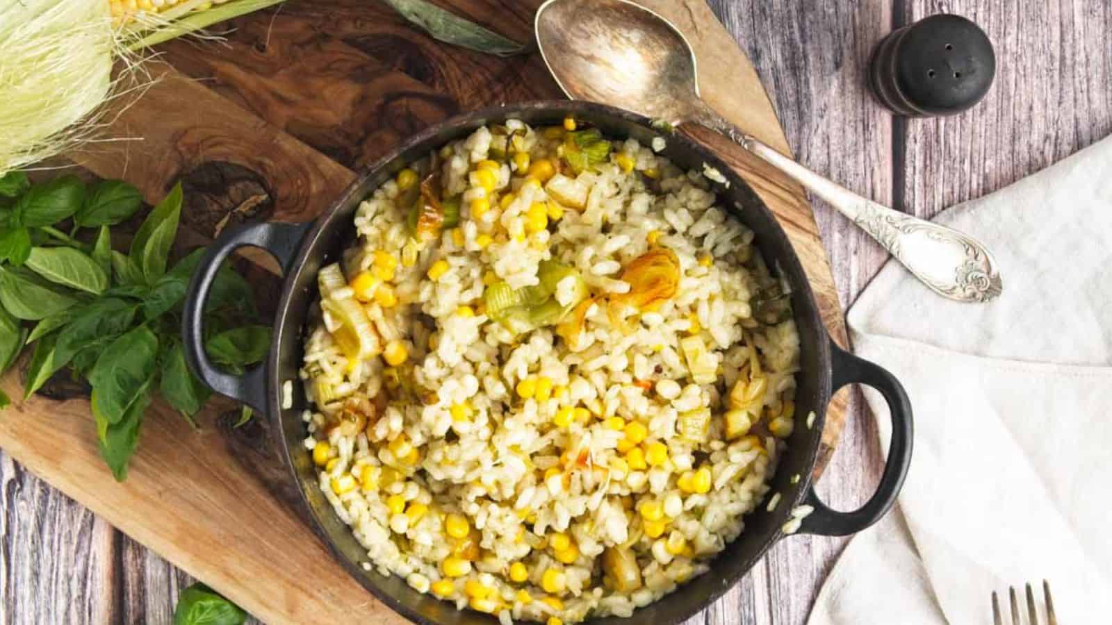 Sweet corn risotto in a skillet on a wooden cutting board.