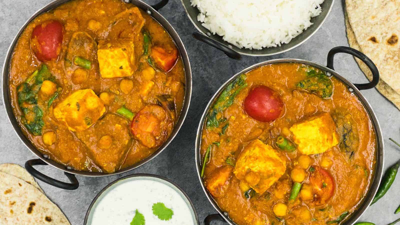 Three bowls of paneer curry with rice and naan.