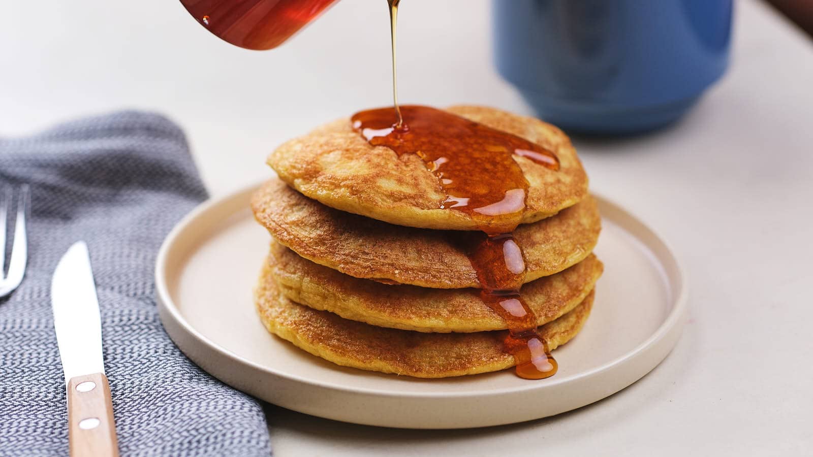 Low carb coconut flour pancakes stacked one white plate.