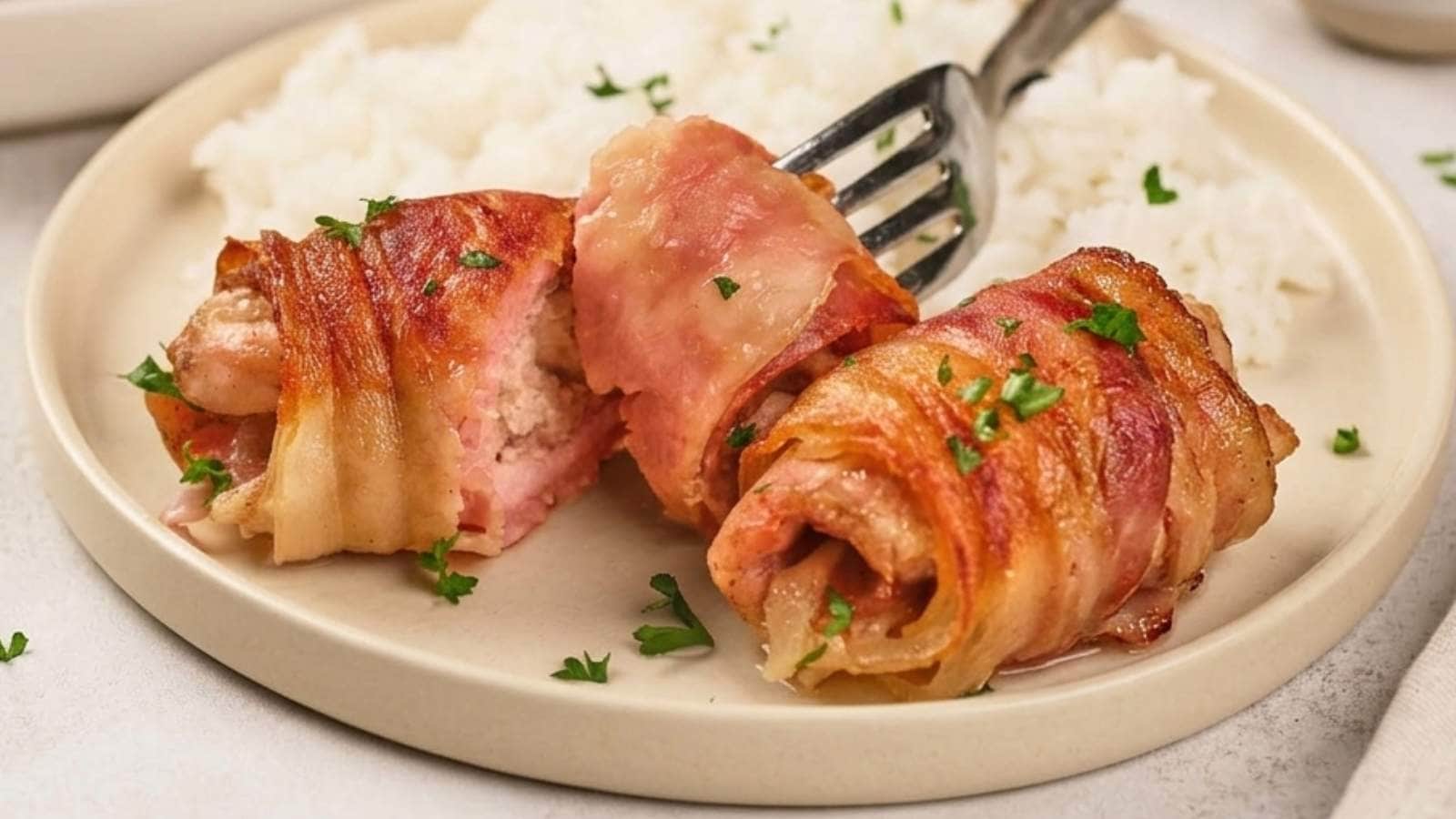 Bacon-wrapped chicken on a white plate with parsley garnish.