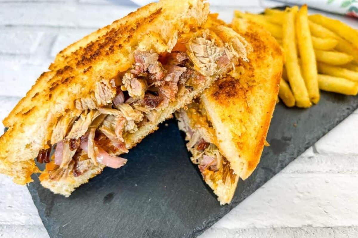 A pulled pork grilled cheese sandwich on a slate plate.
