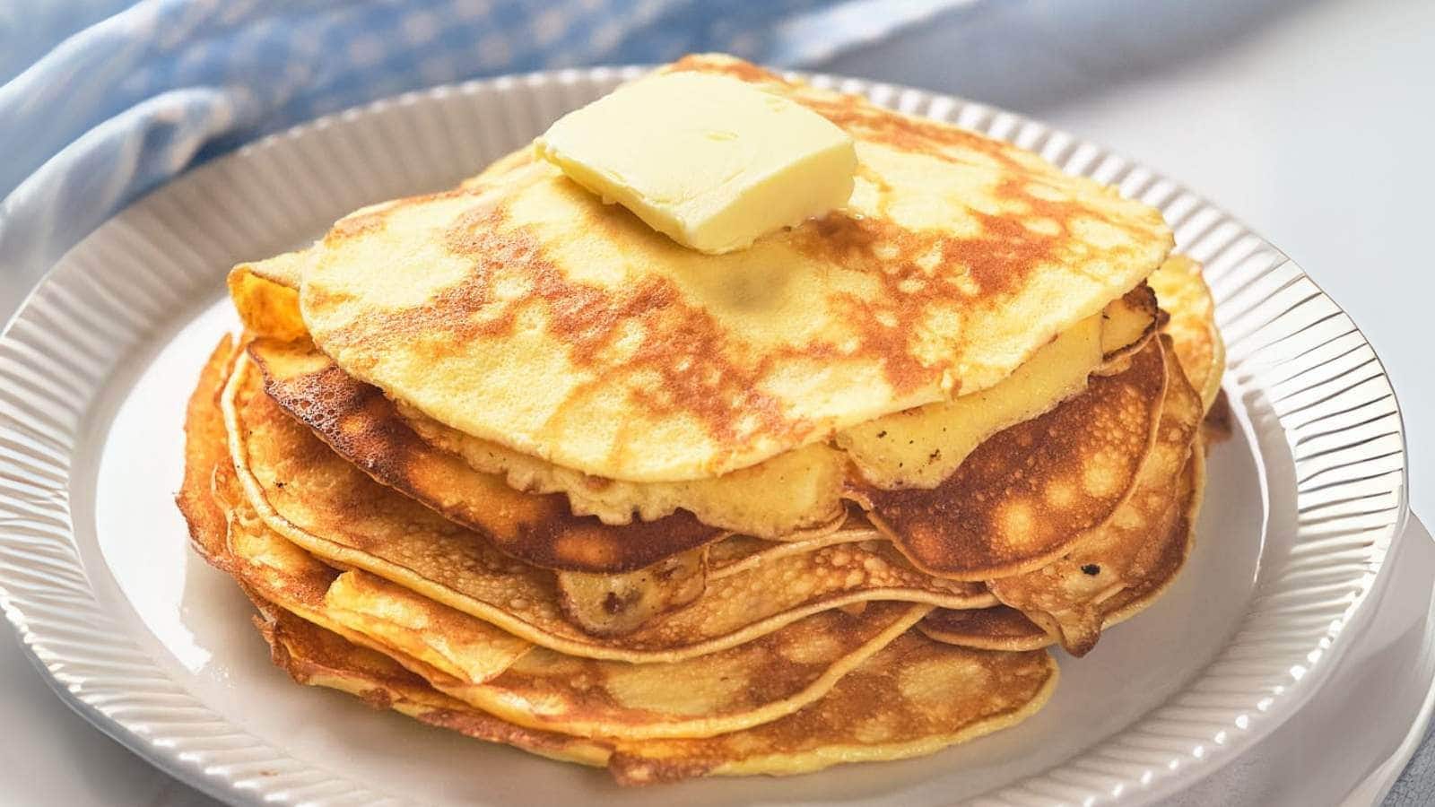A stack of cream cheese pancakes on white plate with butter.