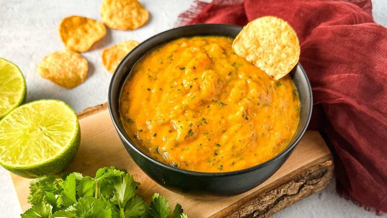 Roasted mango habanero salsa on a wooden cutting board surrounded by lime and cilantro.