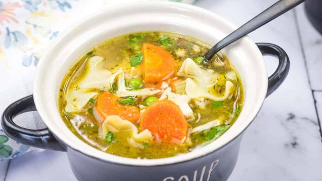 A bowl of Rotisserie Chicken Noodle Soup with a spoon resting inside.