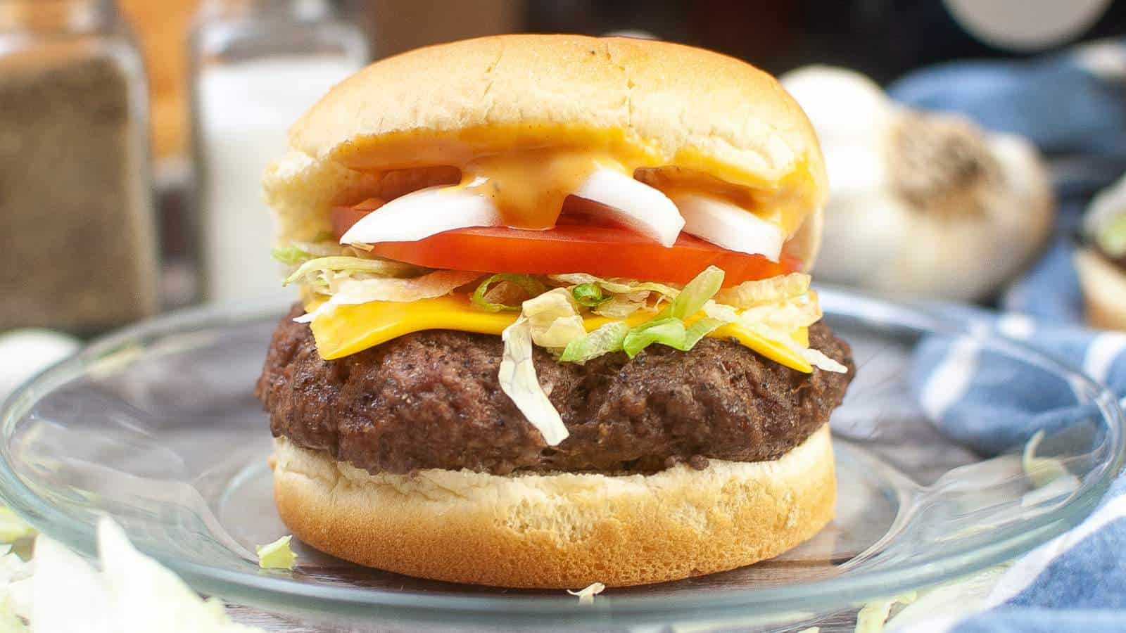 Air fryer cheeseburger with lettuce, tomato, and onion on a bun.