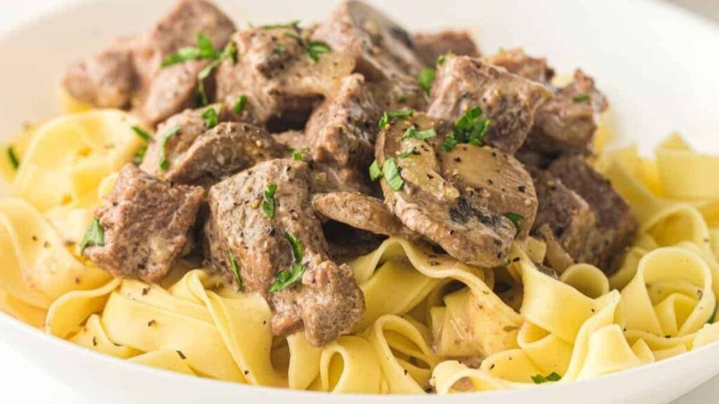A plate of Slow Cooker Beef Stroganoff garnished with chopped parsley.