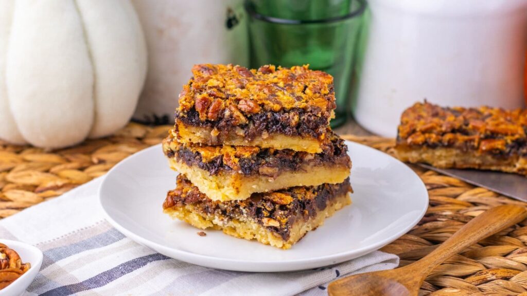 A stack of three pecan pie bars on a white plate.